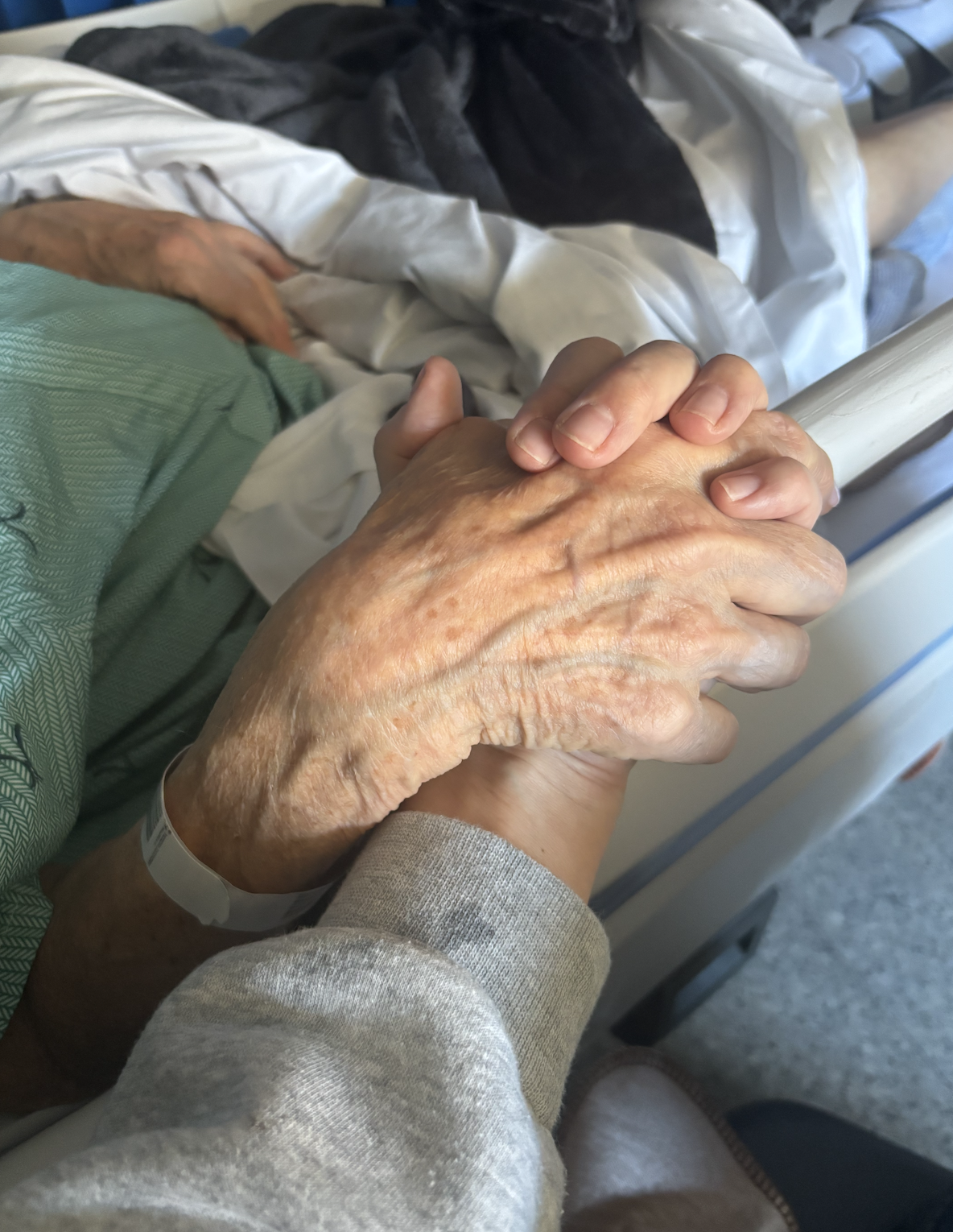 Caregiver holding patient's hand in hospital